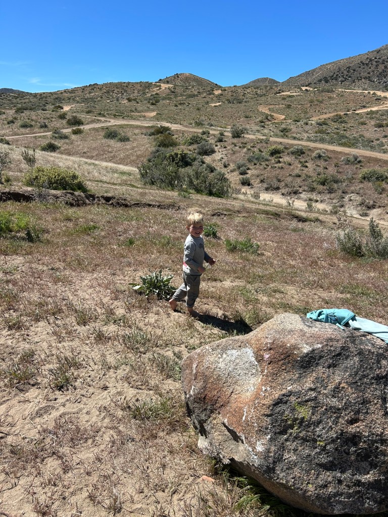 Little one hiking near the rocks with trails in background