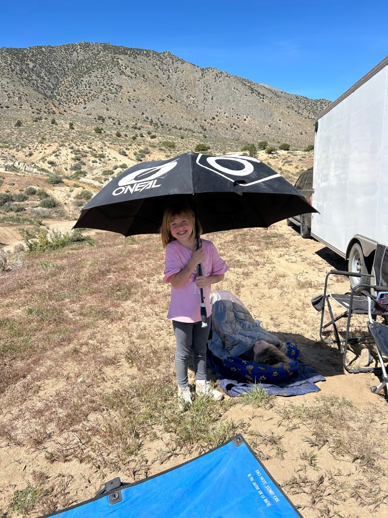 Girl holding O'Neal umbrella smiling with mountains behind